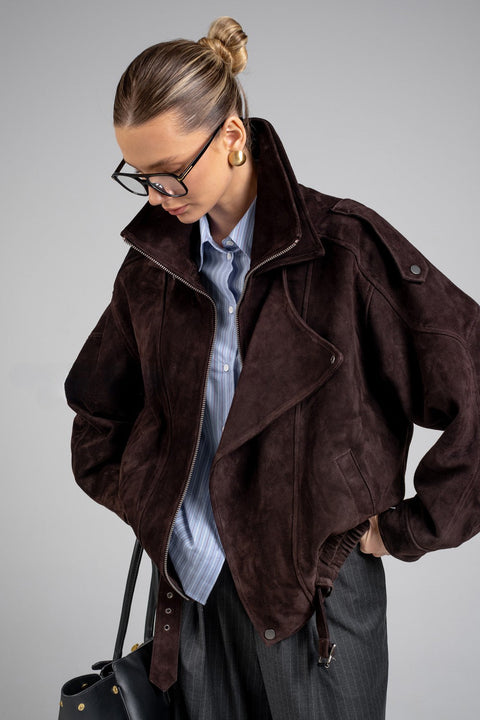 Elegantly dressed, a woman models a suede jacket featuring a high collar and relaxed silhouette, offering both comfort and refined style.