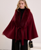 Deep burgundy cashmere cape with plush fox fur details, worn by woman for an elevated cold-weather look.