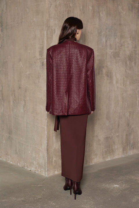 A woman models a burgundy woven blazer with a sleek, tailored fit and strong shoulders, embodying effortless elegance and modern chic.