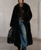 Woman wearing a luxurious long black fox fur coat, styled for bold winter elegance.