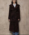 A woman wearing a suede dark brown leather trench coat with a double-breasted front, tailored for a flattering fit and crafted from premium high-quality suede.