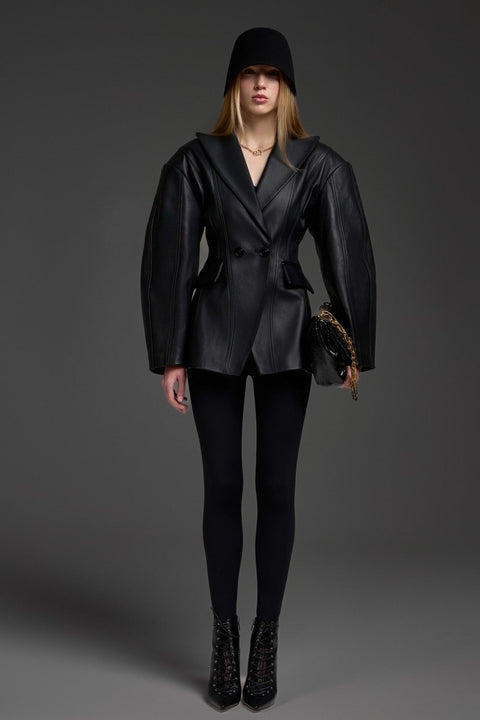 A woman wearing a black leather blazer jacket with a cinched waist, crafted from soft, supple leather for a sleek, feminine silhouette suited for both work and elevated casual style.